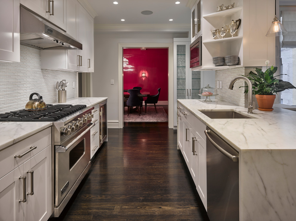 Design ideas for a mid-sized contemporary galley eat-in kitchen in New York with an undermount sink, shaker cabinets, white cabinets, marble benchtops, white splashback, matchstick tile splashback, stainless steel appliances, dark hardwood floors, a peninsula, brown floor and white benchtop.