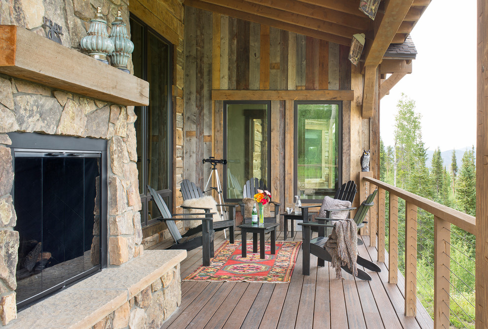 Mid-sized country deck in Denver with with fireplace and a roof extension.