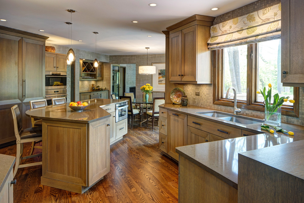 Example of a transitional medium tone wood floor eat-in kitchen design in Chicago with a double-bowl sink, shaker cabinets, medium tone wood cabinets, quartz countertops, gray backsplash, stone tile backsplash, stainless steel appliances and an island