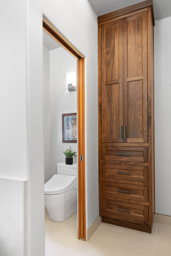 This is an example of a large modern master bathroom in Other with shaker cabinets, medium wood cabinets, a freestanding tub, an alcove shower, a two-piece toilet, white tile, porcelain tile, white walls, porcelain floors, a drop-in sink, quartzite benchtops, white floor, a hinged shower door, white benchtops, a shower seat, a double vanity and a built-in vanity.