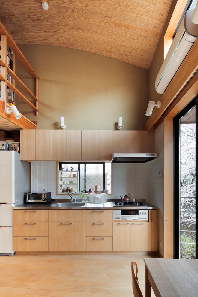 This is an example of a small asian single-wall open plan kitchen in Tokyo Suburbs with a single-bowl sink, flat-panel cabinets, light wood cabinets, grey splashback, light hardwood floors and brown floor.