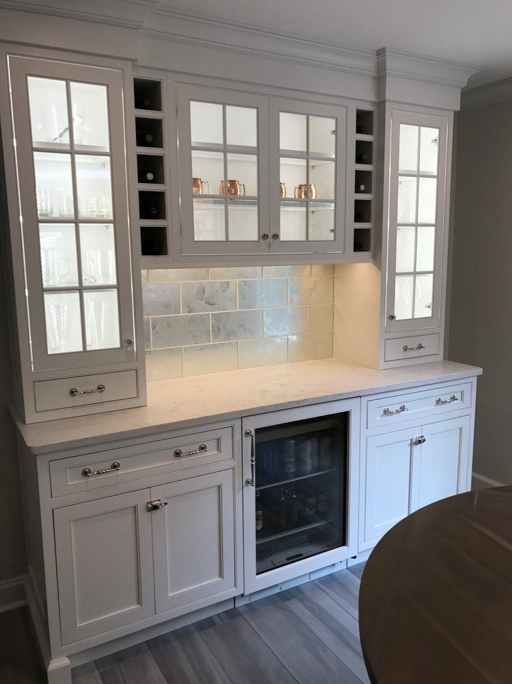Inspiration for a mid-sized transitional u-shaped light wood floor and brown floor open concept kitchen remodel with a farmhouse sink, recessed-panel cabinets, white cabinets, marble countertops, white backsplash, marble backsplash, stainless steel appliances and an island