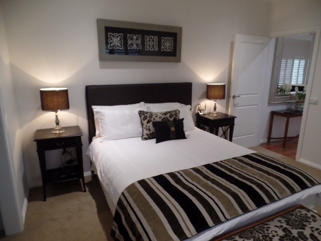 Photo of a transitional master bedroom in Melbourne with white walls and carpet.