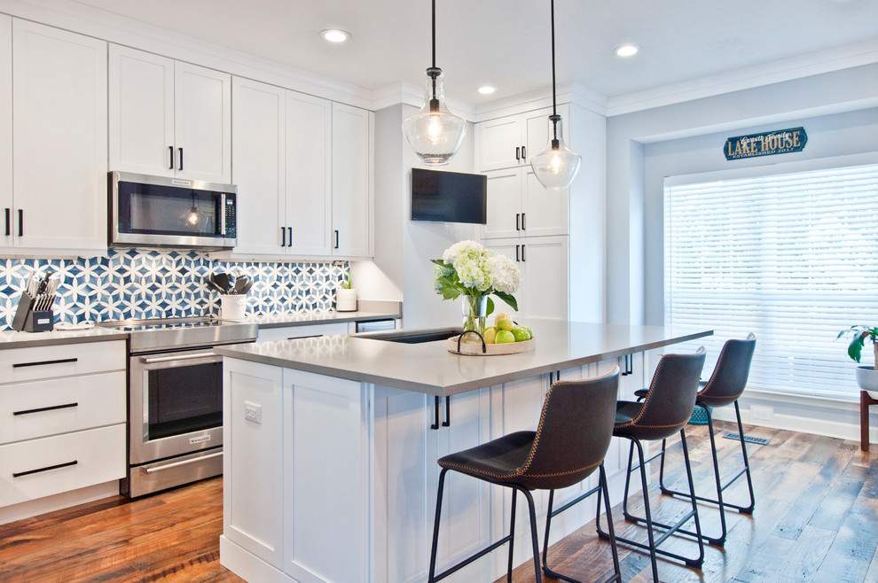 Inspiration for a mid-sized transitional l-shaped separate kitchen in Nashville with an undermount sink, shaker cabinets, white cabinets, quartz benchtops, multi-coloured splashback, mosaic tile splashback, stainless steel appliances, medium hardwood floors, with island, brown floor and grey benchtop.