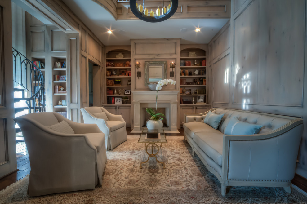This is an example of a large traditional home office in Houston with a library, beige walls, dark hardwood floors, a standard fireplace, a plaster fireplace surround and brown floor.