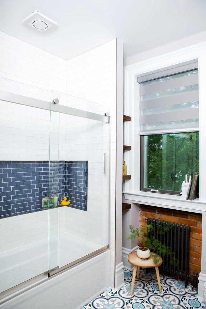 This is an example of a small eclectic 3/4 bathroom in Other with furniture-like cabinets, medium wood cabinets, an alcove tub, an alcove shower, a one-piece toilet, blue tile, ceramic tile, grey walls, concrete floors, an undermount sink, marble benchtops, blue floor and a sliding shower screen.