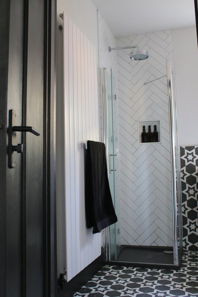 Пример оригинального дизайна: маленькая серо-белая ванная комната в стиле модернизм с плоскими фасадами, серыми фасадами, угловым душем, унитазом-моноблоком, белой плиткой, керамогранитной плиткой, белыми стенами, полом из керамогранита, душевой кабиной, подвесной раковиной, столешницей из плитки, черным полом, тумбой под одну раковину и напольной тумбой для на участке и в саду