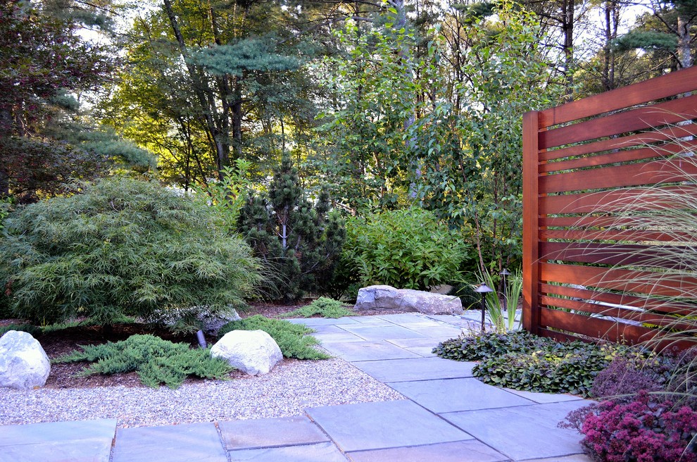 This is an example of a mid-sized asian side yard patio in Boston with a water feature, natural stone pavers and no cover.