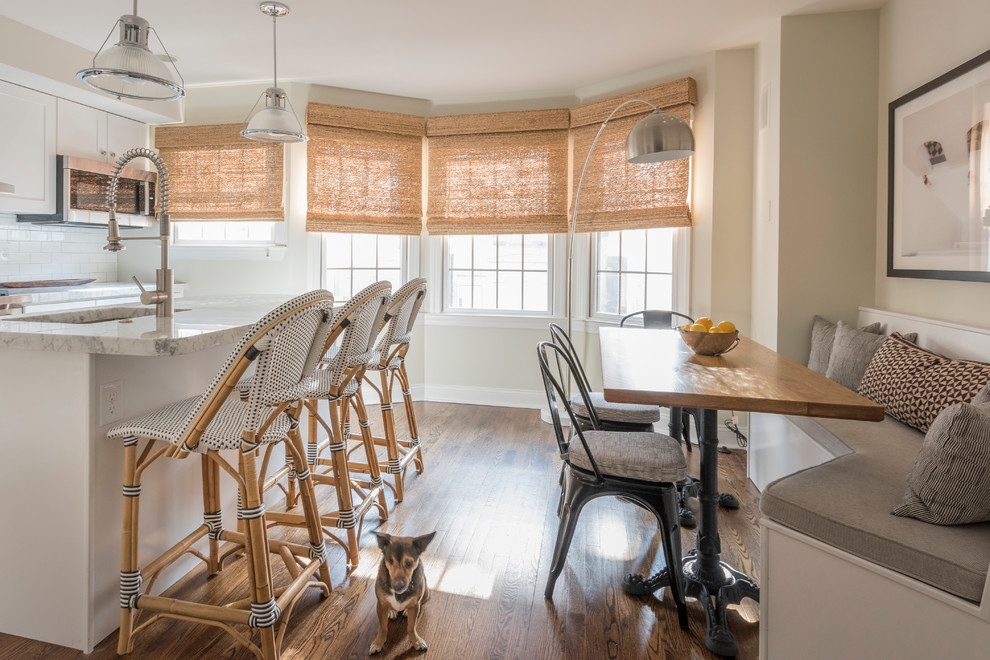 This is an example of a large transitional l-shaped eat-in kitchen in Philadelphia with an undermount sink, shaker cabinets, white cabinets, white splashback, stainless steel appliances, medium hardwood floors, with island and brown floor.