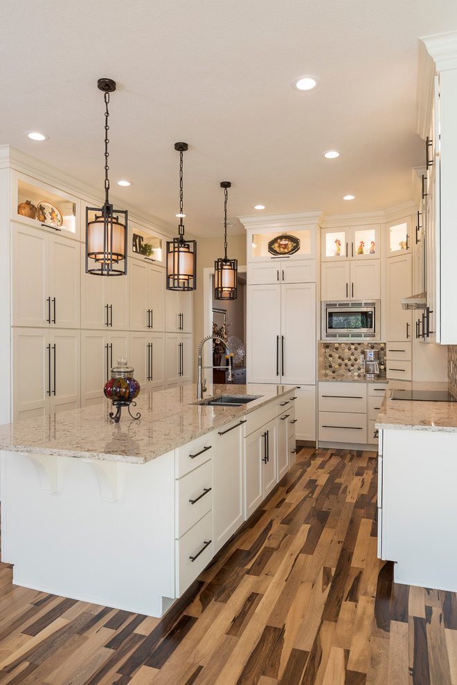 Example of a mid-sized transitional galley light wood floor kitchen pantry design in Dallas with an undermount sink, shaker cabinets, white cabinets, granite countertops, beige backsplash, ceramic backsplash, stainless steel appliances and an island