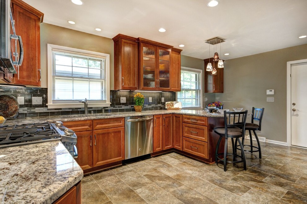 Mid-sized transitional l-shaped vinyl floor enclosed kitchen photo in Milwaukee with an undermount sink, raised-panel cabinets, medium tone wood cabinets, granite countertops, gray backsplash, glass tile backsplash and stainless steel appliances