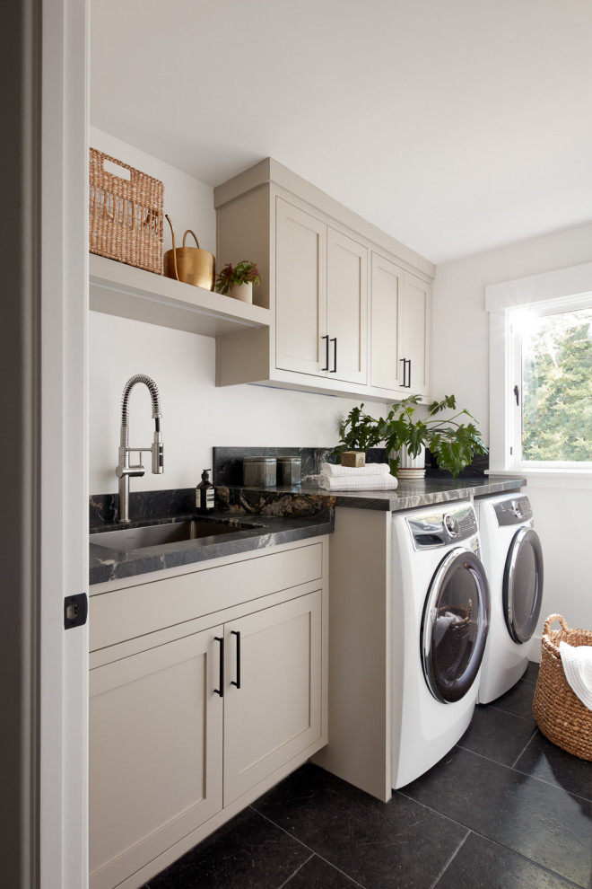 Design ideas for a transitional single-wall laundry room in San Francisco with an undermount sink, shaker cabinets, beige cabinets, black floor and grey benchtop.