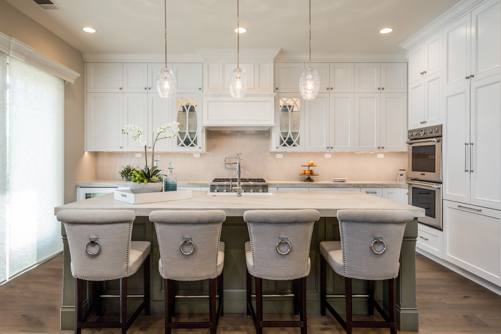 Mid-sized traditional l-shaped kitchen in Orange County with a farmhouse sink, recessed-panel cabinets, grey splashback, ceramic splashback, panelled appliances, with island, brown floor, beige benchtop, white cabinets and dark hardwood floors.