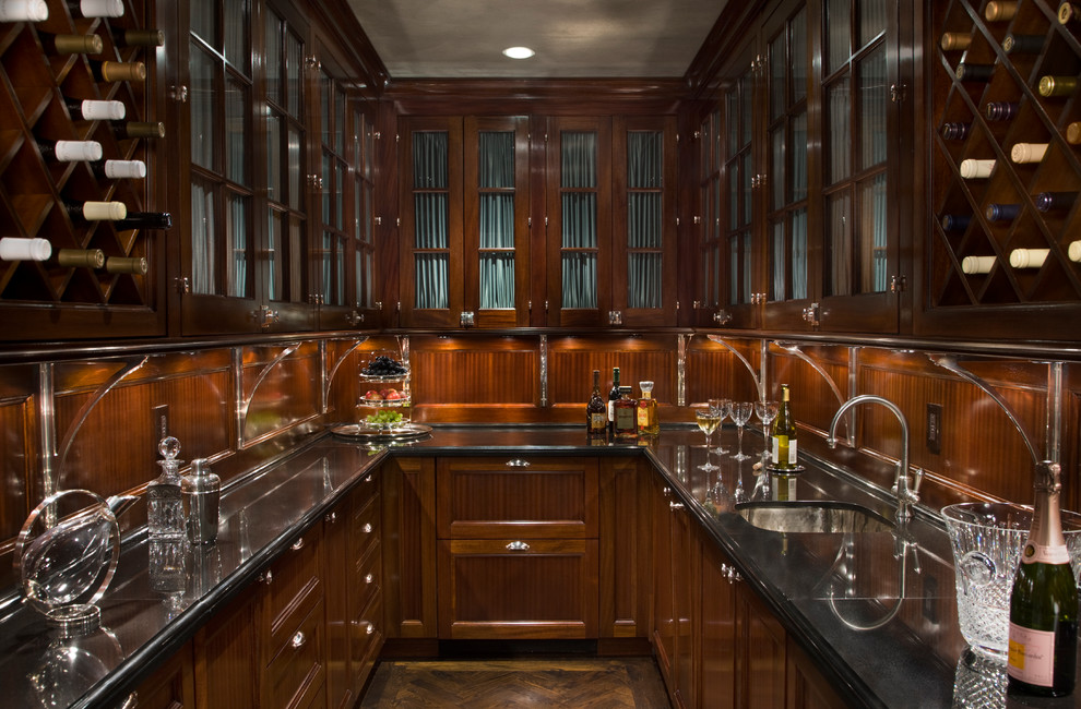 Photo of an expansive traditional u-shaped wet bar in New York with an undermount sink, recessed-panel cabinets, medium wood cabinets, brown splashback and medium hardwood floors.