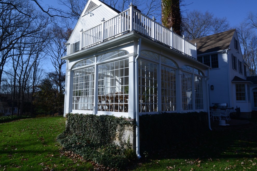 This is an example of a mid-sized traditional sunroom in New York with a standard ceiling, dark hardwood floors, no fireplace and brown floor.