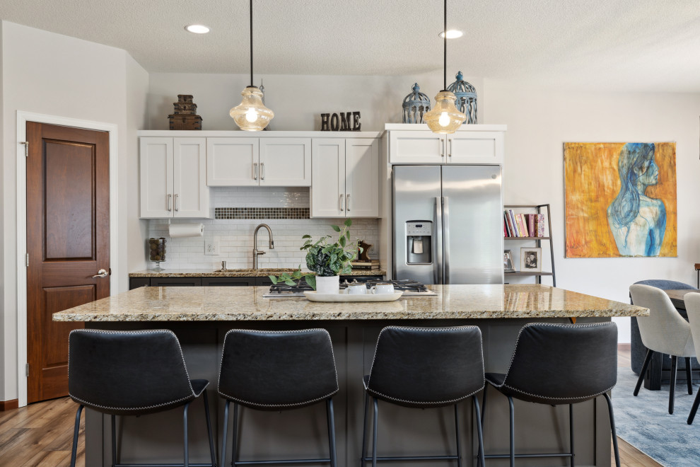 Example of a mid-sized transitional l-shaped vinyl floor and brown floor eat-in kitchen design in Minneapolis with a double-bowl sink, shaker cabinets, white cabinets, granite countertops, white backsplash, ceramic backsplash, stainless steel appliances, an island and brown countertops