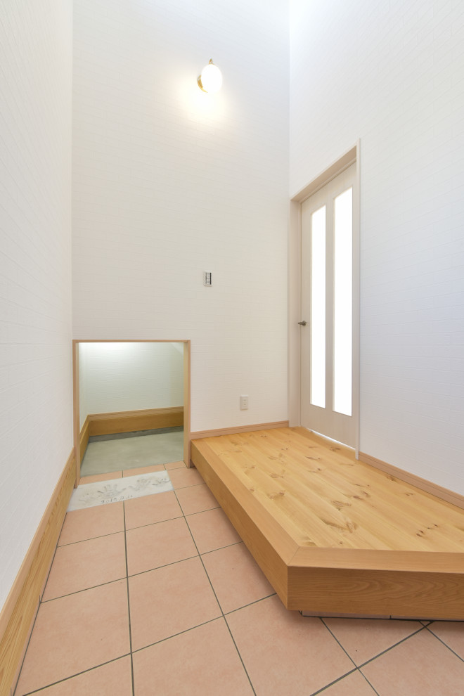Photo of a large beach style entry hall in Other with white walls, terra-cotta floors, a single front door, a medium wood front door, pink floor, wallpaper and wallpaper.