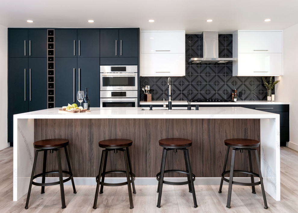 Design ideas for a mid-sized contemporary single-wall open plan kitchen in Los Angeles with a single-bowl sink, flat-panel cabinets, black cabinets, quartz benchtops, black splashback, ceramic splashback, panelled appliances, vinyl floors, with island, beige floor and white benchtop.