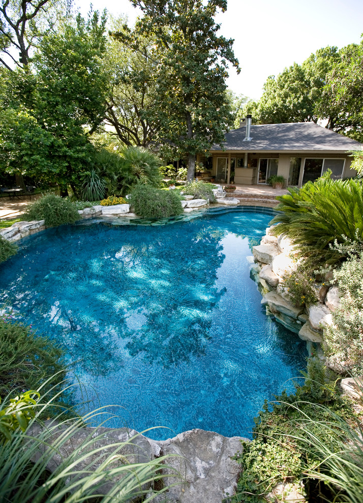 Inspiration for a mid-sized country backyard custom-shaped natural pool in Austin with brick pavers and a hot tub.