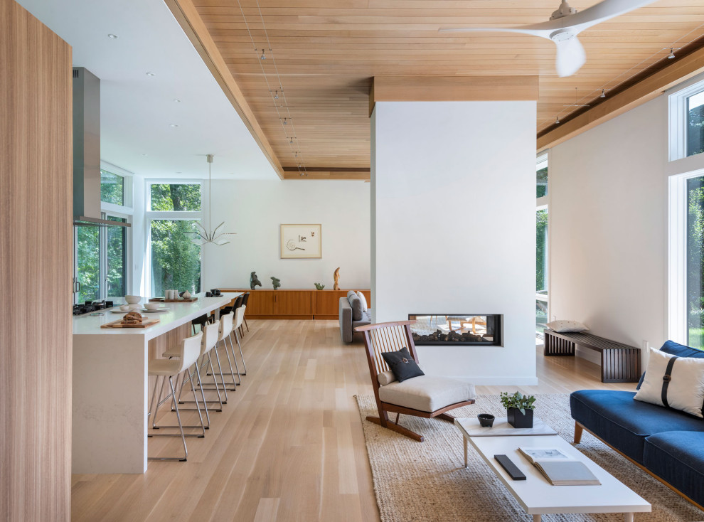 Mid-sized midcentury open concept living room in Boston with white walls, light hardwood floors, a two-sided fireplace, beige floor and wood.