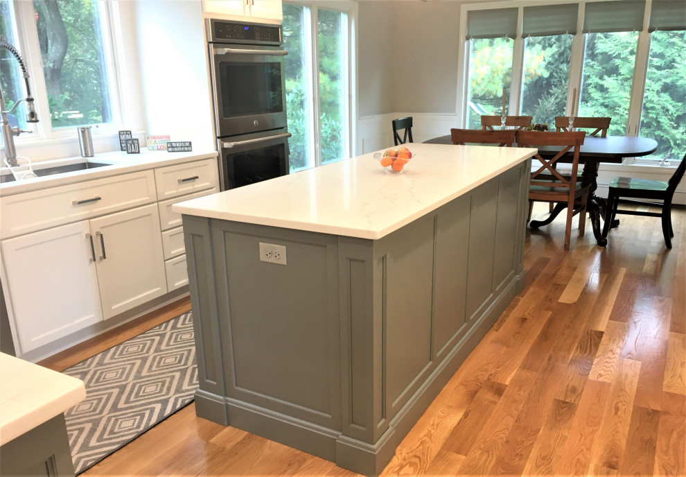 Eat-in kitchen - large transitional galley light wood floor and brown floor eat-in kitchen idea in Boston with an undermount sink, shaker cabinets, white cabinets, quartz countertops, white backsplash, subway tile backsplash, stainless steel appliances, two islands and white countertops