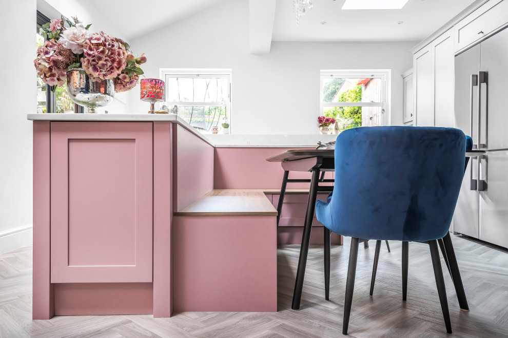 Design ideas for a mid-sized eclectic l-shaped eat-in kitchen in Berkshire with a single-bowl sink, shaker cabinets, pink cabinets, quartzite benchtops, white splashback, panelled appliances, with island and white benchtop.