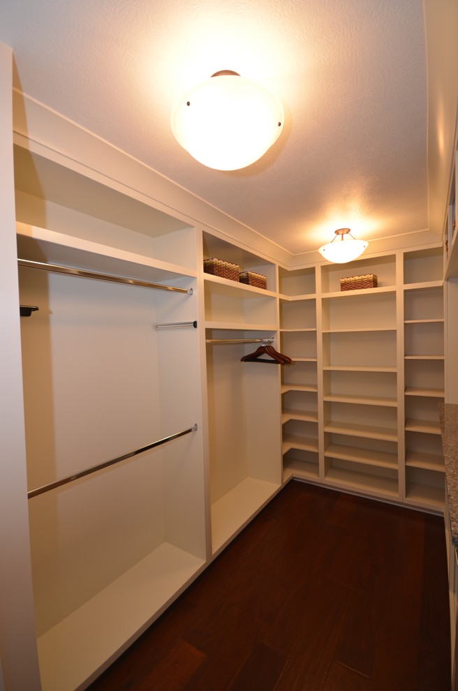 Mid-sized modern gender-neutral walk-in wardrobe in Grand Rapids with open cabinets, white cabinets and dark hardwood floors.