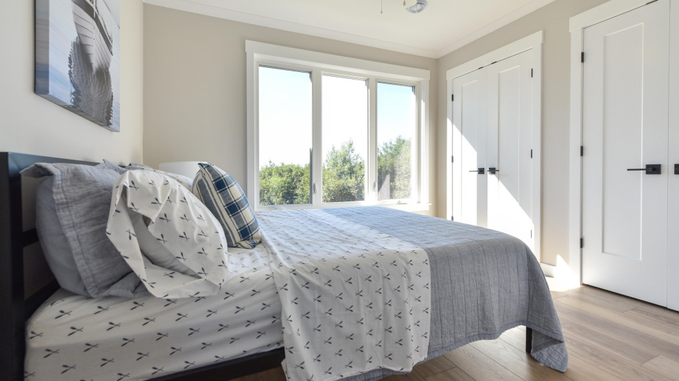 Foto de dormitorio costero de tamaño medio con paredes beige, suelo laminado y suelo marrón