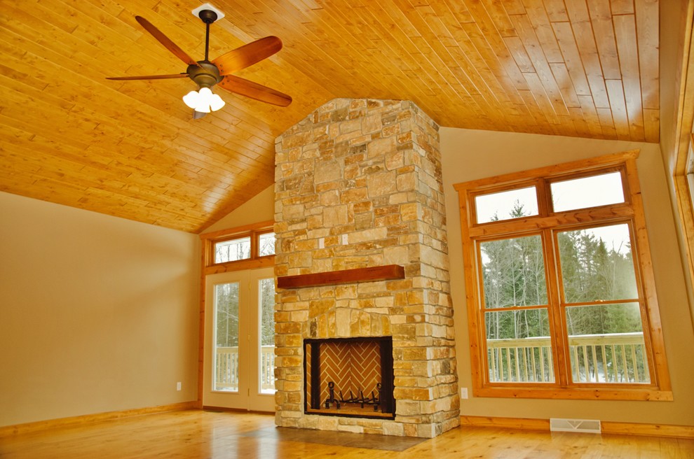 Example of a large mountain style open concept light wood floor and brown floor home design design with beige walls, a wood stove and a stone fireplace