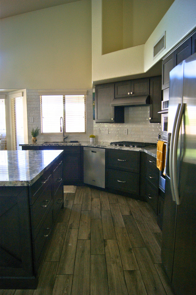 Mid-sized minimalist l-shaped porcelain tile and gray floor open concept kitchen photo in Phoenix with an undermount sink, shaker cabinets, brown cabinets, granite countertops, white backsplash, subway tile backsplash, stainless steel appliances, an island and white countertops