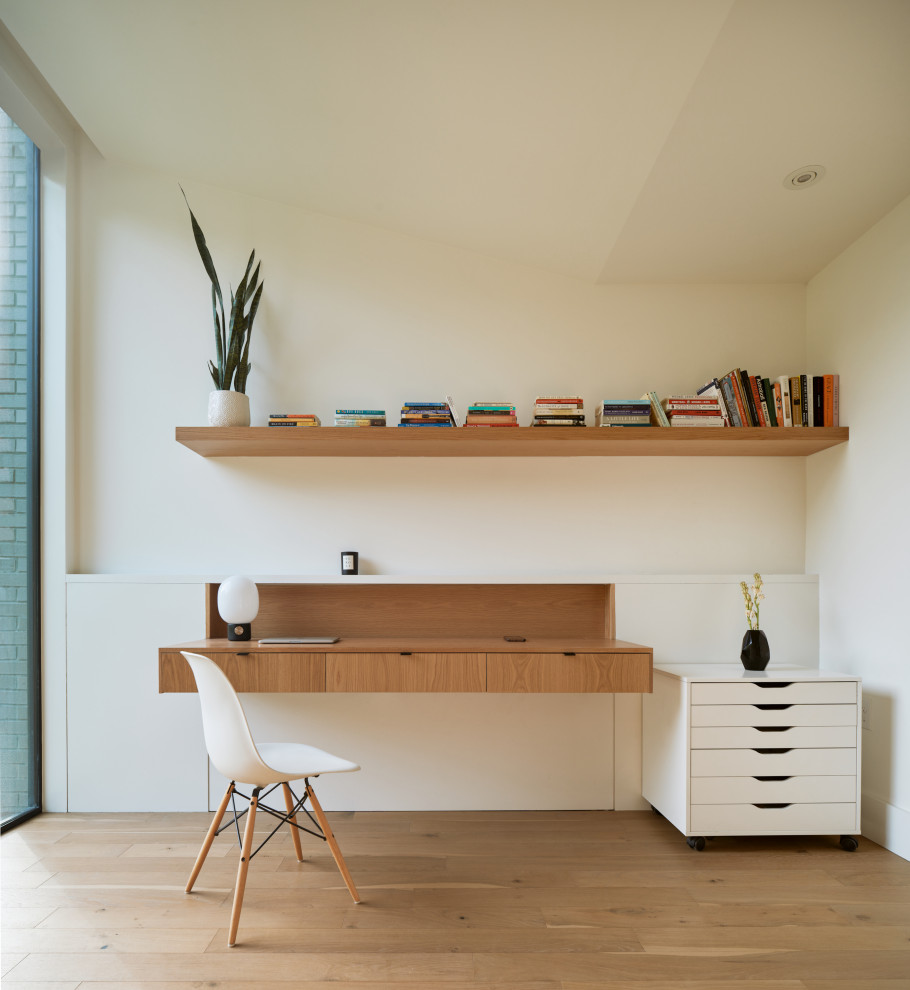 Minimalist medium tone wood floor, brown floor and vaulted ceiling home office photo in Austin with white walls