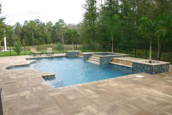 Example of a large backyard concrete paver and custom-shaped hot tub design in Jacksonville