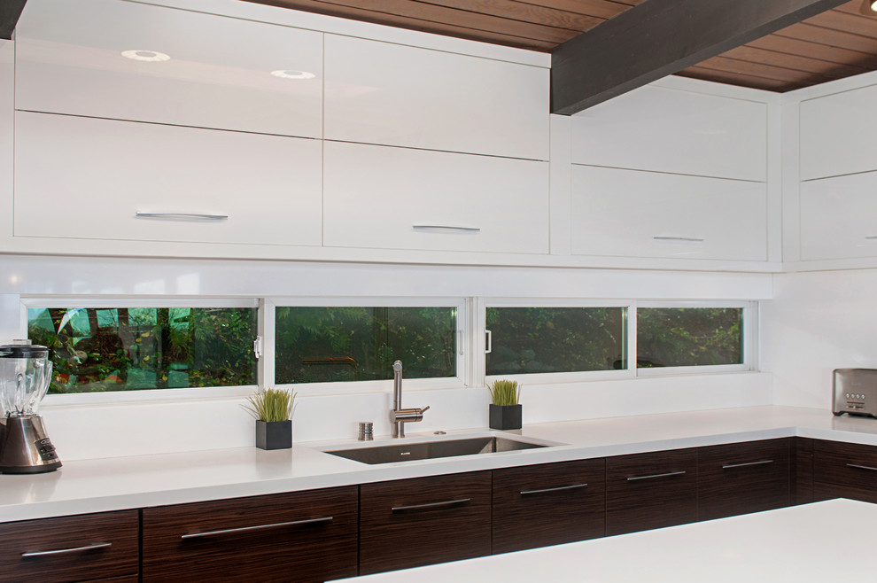 Mid-sized midcentury u-shaped eat-in kitchen in San Diego with a single-bowl sink, flat-panel cabinets, dark wood cabinets, solid surface benchtops, white splashback, stainless steel appliances and with island.