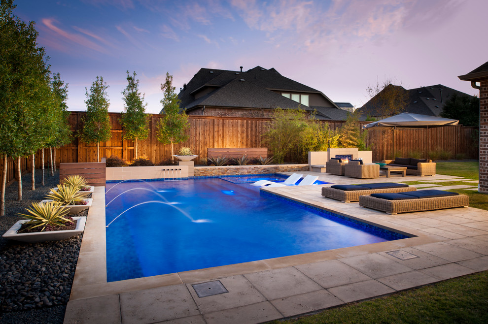 This is an example of a large modern backyard custom-shaped pool in Dallas with a hot tub.