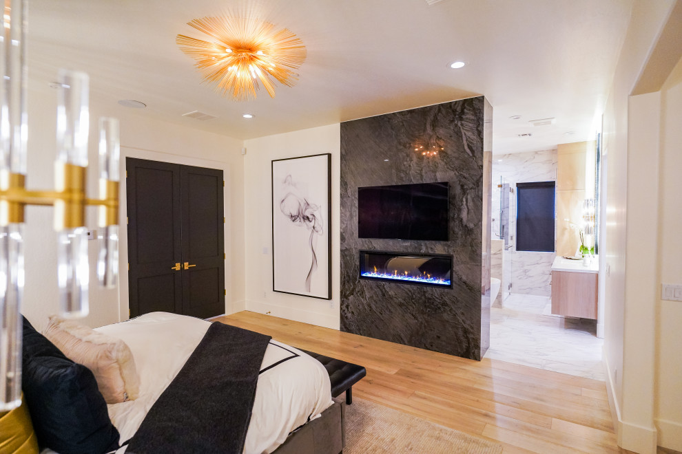 Cette image montre une chambre parentale minimaliste avec une cheminée double-face et un manteau de cheminée en pierre.