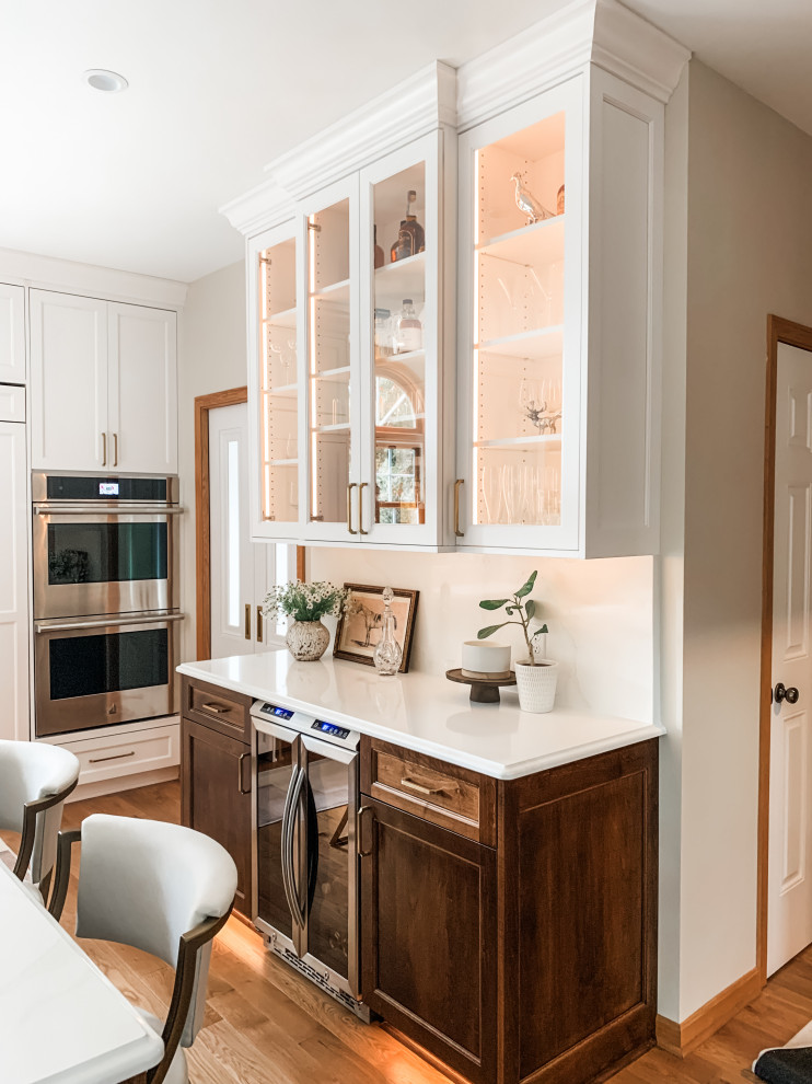 Kitchen - light wood floor kitchen idea with a double-bowl sink, shaker cabinets, white cabinets, quartz countertops, quartz backsplash, paneled appliances and an island