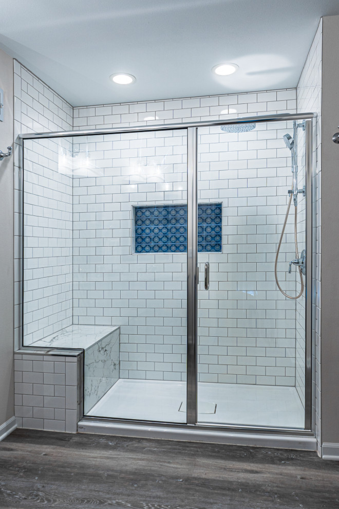 Inspiration for a mid-sized timeless master white tile and subway tile vinyl floor, brown floor and double-sink alcove shower remodel in Milwaukee with shaker cabinets, blue cabinets, beige walls, an undermount sink, marble countertops, a hinged shower door, multicolored countertops, a niche and a freestanding vanity