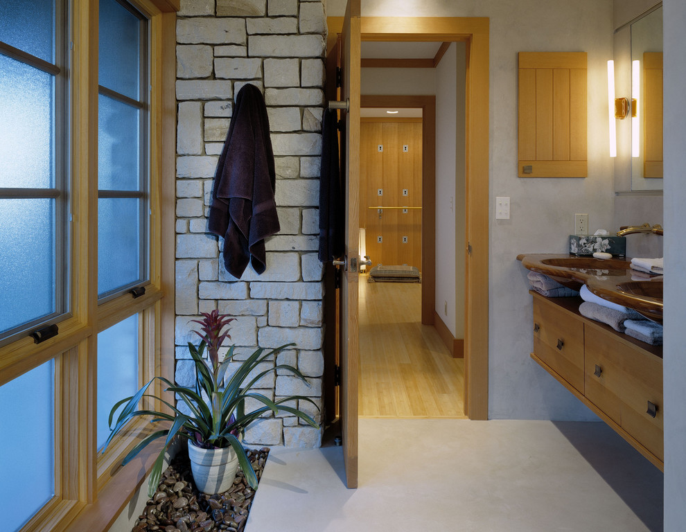 Photo of a large contemporary master bathroom in Seattle with an integrated sink, flat-panel cabinets, light wood cabinets, grey walls, concrete floors, glass benchtops and grey floor.