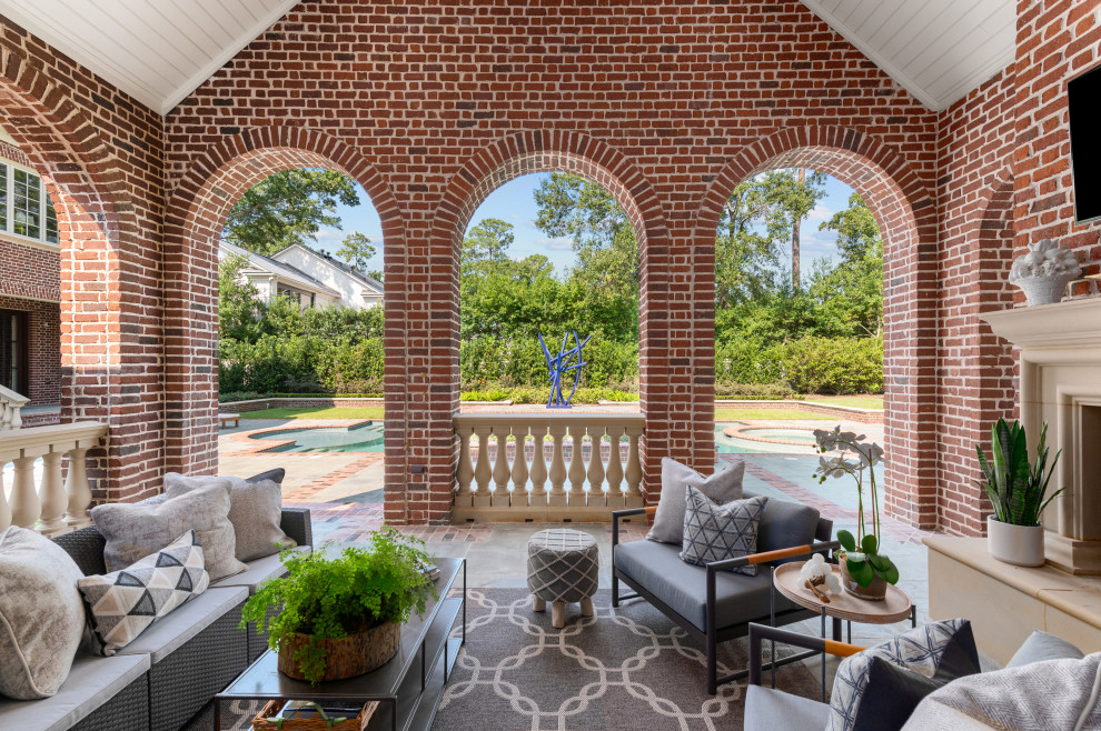 Esempio di un grande patio o portico chic dietro casa con un caminetto, pavimentazioni in pietra naturale e un tetto a sbalzo