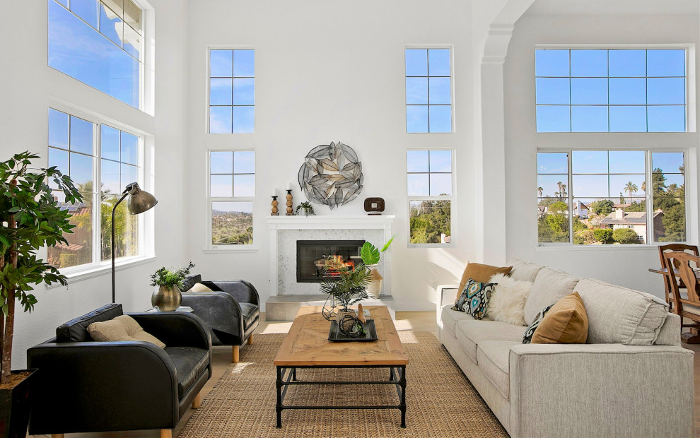 This is an example of a transitional open concept living room in San Diego with white walls, a standard fireplace, a tile fireplace surround and beige floor.