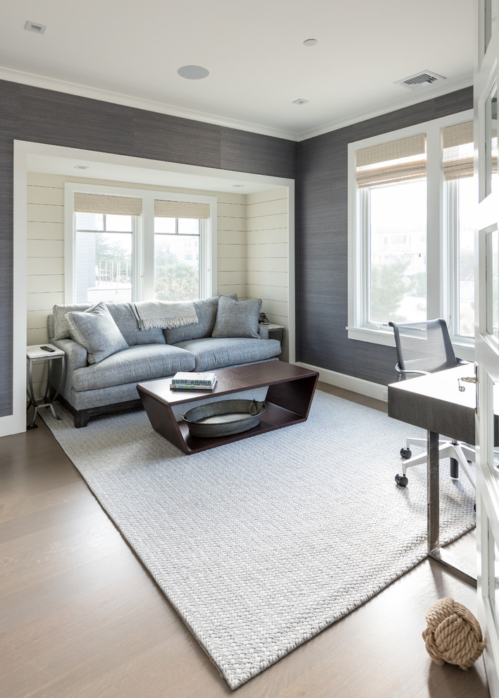 This is an example of a mid-sized beach style study room in New York with grey walls, light hardwood floors, no fireplace, a freestanding desk and beige floor.