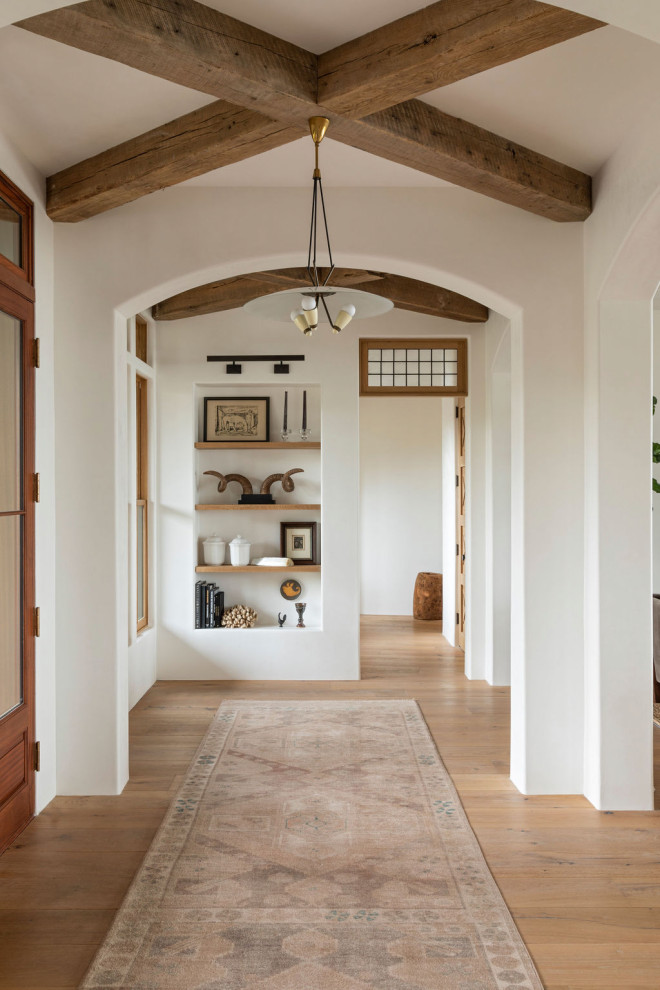 Design ideas for a large mediterranean front door in Charleston with white walls, light hardwood flooring, brown floors and exposed beams.
