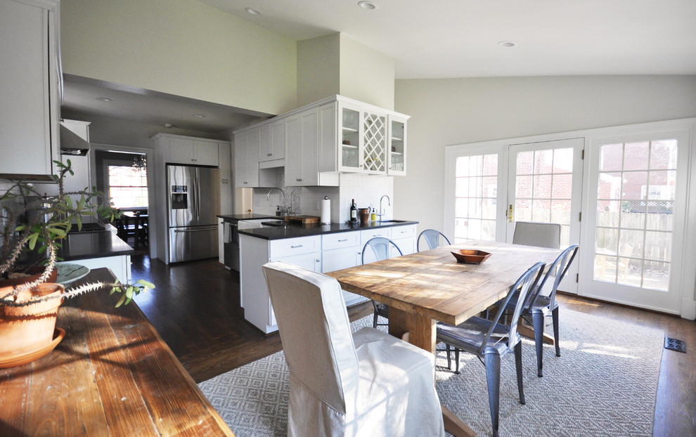 Example of a mid-sized transitional l-shaped medium tone wood floor home design design in Richmond with a farmhouse sink, shaker cabinets, white cabinets, granite countertops, white backsplash, subway tile backsplash and stainless steel appliances