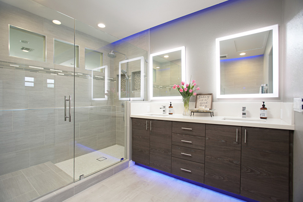 Large minimalist master gray tile and porcelain tile porcelain tile and gray floor corner shower photo in San Diego with raised-panel cabinets, dark wood cabinets, a two-piece toilet, gray walls, an undermount sink, quartzite countertops and a hinged shower door