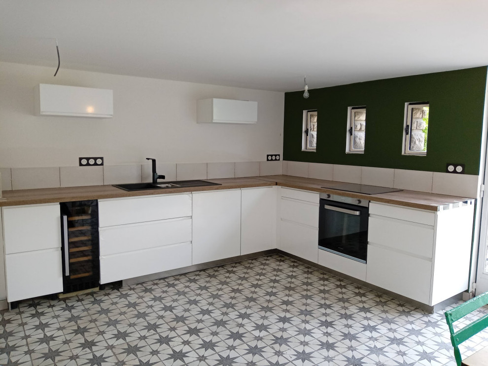 This is an example of a large contemporary l-shaped enclosed kitchen in Paris with wood worktops, white splashback and no island.