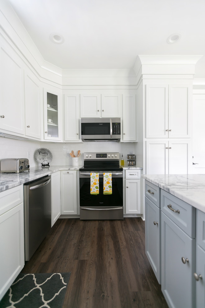Inspiration for a timeless u-shaped brown floor eat-in kitchen remodel in Charleston with an undermount sink, shaker cabinets, white cabinets, white backsplash, stainless steel appliances, an island and white countertops