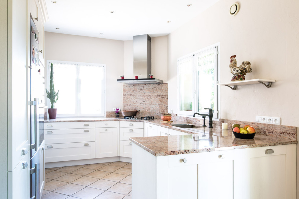 This is an example of a country kitchen in Lyon with a single-bowl sink, recessed-panel cabinets, white cabinets, granite benchtops, pink splashback and stainless steel appliances.