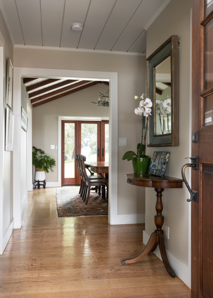 Réalisation d'un grand hall d'entrée champêtre avec un mur blanc, une porte simple, une porte marron et un plafond en lambris de bois.