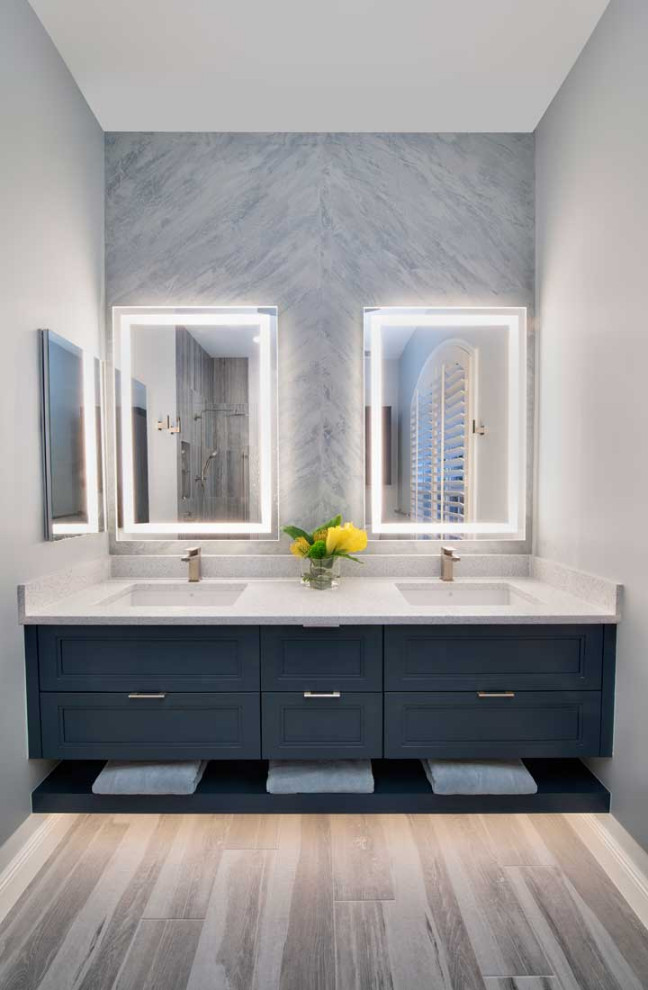 Inspiration for a large contemporary ensuite bathroom in Miami with blue cabinets, a two-piece toilet, grey tiles, ceramic tiles, grey walls, ceramic flooring, a submerged sink, engineered stone worktops, grey floors, an open shower, white worktops, double sinks, a floating vanity unit, a corner shower and recessed-panel cabinets.
