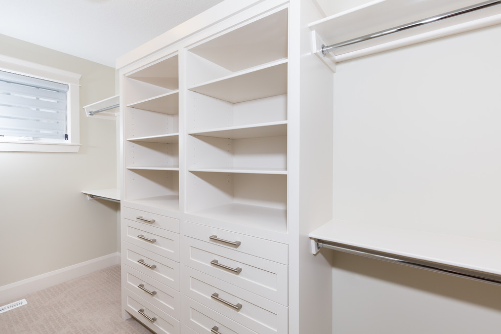 Photo of a mid-sized traditional gender-neutral walk-in wardrobe in Calgary with shaker cabinets, white cabinets, carpet and beige floor.